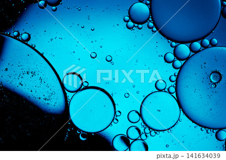 Oil drops creating an abstract pattern on a vibrant blue water surface Oil drops creating an abstract pattern on a vibrant blue water surface 141634039