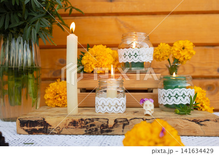 Day of Dead altar with lit candles marigold blooms and decorative jars on rustic wooden table, with day, dead, mexico, background detail, showing spanish, tradition, altar, authentic context Day of Dead altar with lit candles marigold blooms and decorative jars on rustic wooden table, with day, dead, mexico, background detail, showing spanish, tradition, altar, authentic context 141634429