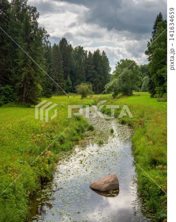 Scenic Slavyanka river flowing through the lush green meadows of Pavlovsk Park, Saint Petersburg, Russia. Scenic Slavyanka river flowing through the lush green meadows of Pavlovsk Park, Saint Petersburg, Russia. 141634659