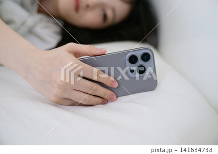 スマホのアラームを止める寝起きの20代日本人女性 スマホのアラームを止める寝起きの20代日本人女性 141634738