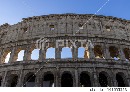 Famous Coliseum in Rome. Colosseum, or Coliseum. Part of the wall of an antique stone structure with arches. Italy, Europe. Famous touristic place in the world, Europe. Beautiful blue sky background. Famous Coliseum in Rome. Colosseum, or Coliseum. Part of the wall of an antique stone structure with arches. Italy, Europe. Famous touristic place in the world, Europe. Beautiful blue sky background. 141635338