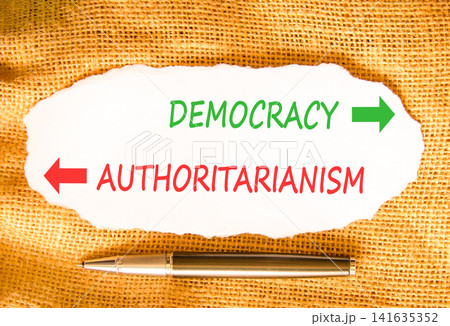 Democracy or authoritarianism words symbol. Concept words Democracy Authoritarianism on beautiful white paper. Beautiful canvas background. Business democracy authoritarianism concept. Copy space 141635352