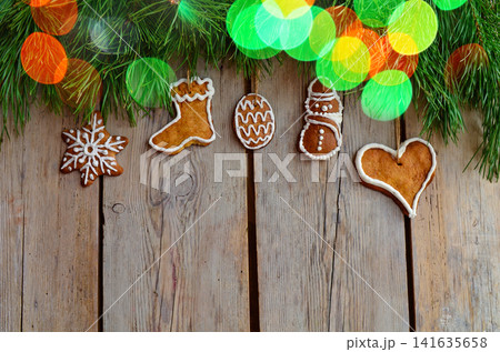 Royal icing cookies. Christmas gingerbread cookies on wooden table top view. Flat lay of Christmas gingerbread cookies on wooden background. Sprinkle accents introduce vibrant contrast. 141635658