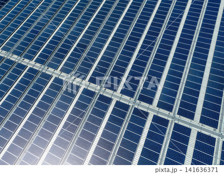 Aerial view of solar panels or photovoltaics on factory roof. Solar power for green energy. Sustainable renewable energy. Solar cell panels generate electricity from sun lights. Photovoltaics or PV. 141636371