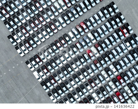 Aerial view of new cars stock at factory parking lot. Above view cars parked in a row. Automotive industry. Logistics business. Import or export new cars at warehouse. Big parking lot at port terminal Aerial view of new cars stock at factory parking lot. Above view cars parked in a row. Automotive industry. Logistics business. Import or export new cars at warehouse. Big parking lot at port terminal 141636422