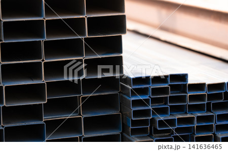 Industrial warehouse stock of rectangular metal pipes for building and construction supplies. Stack of steel pipes. Iron materials for construction and infrastructure projects. Steel tubing storage. Industrial warehouse stock of rectangular metal pipes for building and construction supplies. Stack of steel pipes. Iron materials for construction and infrastructure projects. Steel tubing storage. 141636465
