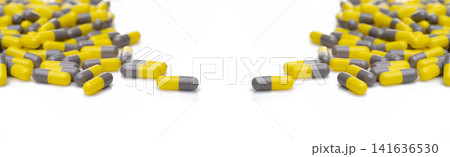 Yellow and gray probiotic capsule pill on white background. Probiotic supplement. Gut health. Dietary supplements. Probiotics for a healthy gut. Lactobacillus acidophilus and Bifidobacterium animalis. 141636530