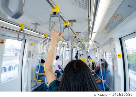 Woman hand firm grip safety handrail in elevated monorail train. Mass transit system in modern city. Inside of electric train. Tourist travel by city sky train. Public transportation. Urban transport. Woman hand firm grip safety handrail in elevated monorail train. Mass transit system in modern city. Inside of electric train. Tourist travel by city sky train. Public transportation. Urban transport. 141636559