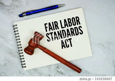 Fair Labor Standards Act text written on notepad with pen and judge gavel on marble background Fair Labor Standards Act text written on notepad with pen and judge gavel on marble background 141636687