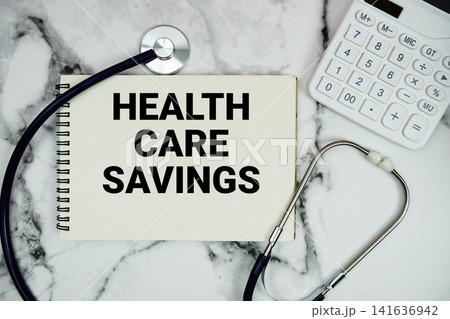Health Care Savings text written on notepad with stethoscope and calculator on marble background Health Care Savings text written on notepad with stethoscope and calculator on marble background 141636942