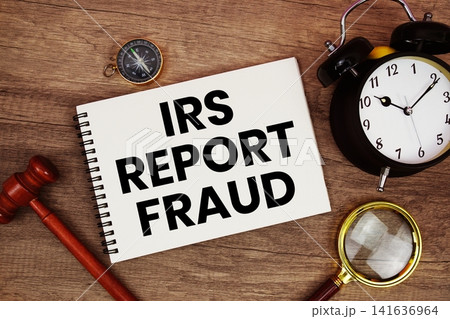 IRS Report Fraud message written on notepad with alarm clock, wood gavel and magnifying glass flat lay on wooden background IRS Report Fraud message written on notepad with alarm clock, wood gavel and magnifying glass flat lay on wooden background 141636964