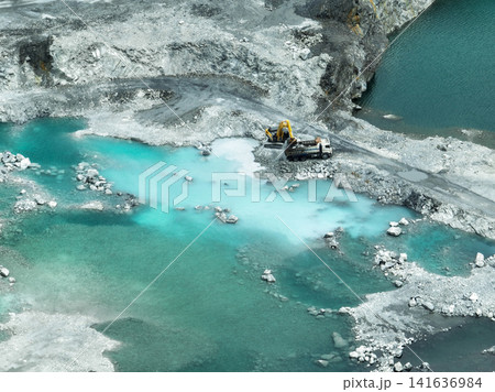 Open pit mine industry. Limestone quarry with backhoe and truck in operation. Heavy machinery in mining industry and construction material supply. Landscape of resource extraction in a industrial site 141636984