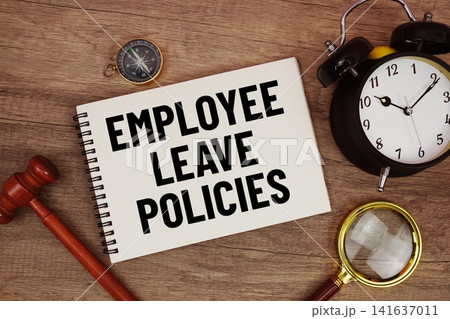 Employee Leave Policies message written on notepad with alarm clock, wood gavel and magnifying glass flat lay on wooden background 141637011