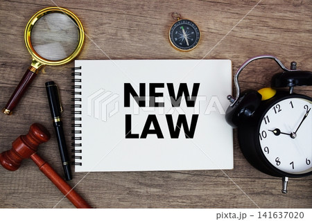 New Law message written on notepad with alarm clock, wood gavel and magnifying glass flat lay on wooden background 141637020
