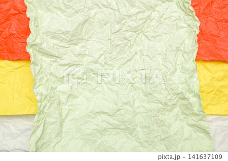 crumpled light green paper on top of layers of orange yellow and white paper 141637109