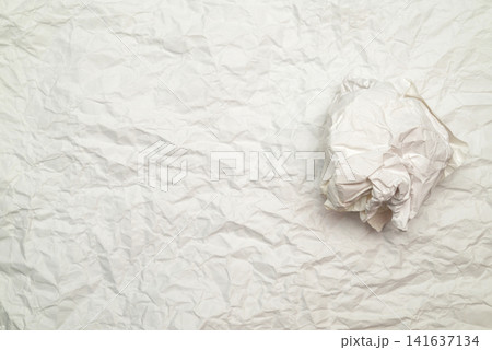 one crumpled white paper ball lying on right side of creped light sheet field one crumpled white paper ball lying on right side of creped light sheet field 141637134