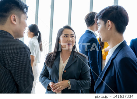 Businesswoman leading a discussion with colleagues during networking session in corporate office. Communication, teamwork, leadership, collaboration, professional relationships, and business success. Businesswoman leading a discussion with colleagues during networking session in corporate office. Communication, teamwork, leadership, collaboration, professional relationships, and business success. 141637334