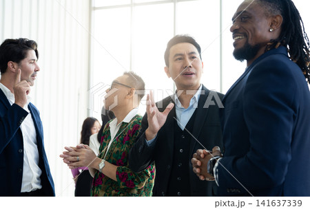 Multicultural business professionals networking and exchanging ideas during corporate event. Professional communication, leadership, teamwork, collaboration, diversity, and business relationships. Multicultural business professionals networking and exchanging ideas during corporate event. Professional communication, leadership, teamwork, collaboration, diversity, and business relationships. 141637339
