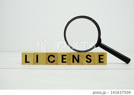LICENSE alphabet letters with magnifying glass on wooden background LICENSE alphabet letters with magnifying glass on wooden background 141637509