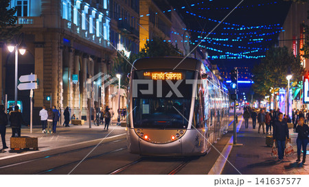 Nice, France - November 2, 2018 - Tram at night on Massena square with pedestrians Nice, France - November 2, 2018 - Tram at night on Massena square with pedestrians 141637577