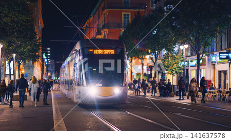Nice, France - November 2, 2018 - Tram at night on Massena square with pedestrians Nice, France - November 2, 2018 - Tram at night on Massena square with pedestrians 141637578