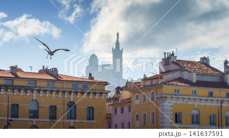Basilique Notre-Dame de la Garde in the foggy background with red tiled roof Marseille houses	 141637591