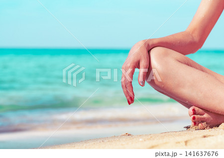 Close up of woman relaxing on a tropical sandy beach with turquoise ocean background, peaceful summer vacation, wellness lifestyle, luxury seaside destination. Wellness retreat, relaxation concept. Close up of woman relaxing on a tropical sandy beach with turquoise ocean background, peaceful summer vacation, wellness lifestyle, luxury seaside destination. Wellness retreat, relaxation concept. 141637676