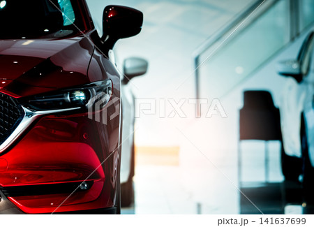 Front view of a modern red passenger car in luxury automobile showroom. Automotive retail, vehicle sales, transportation business and dealership concept. Automotive industry. Vehicle retail. Front view of a modern red passenger car in luxury automobile showroom. Automotive retail, vehicle sales, transportation business and dealership concept. Automotive industry. Vehicle retail. 141637699