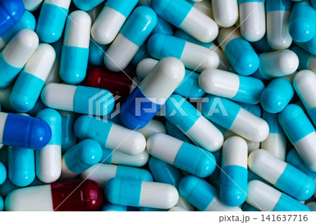 Blue pharmaceutical capsules with unique red capsule. Personalized medicine, pharmaceutical innovation, precision healthcare, clinical research and modern drug development. Drug innovation. 141637716