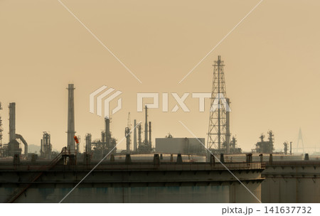 Oil refinery and petrochemical industrial plant under hazy sky with visible air pollution. Environmental impact, greenhouse gas emissions, fossil fuel production and climate change concept. Oil refinery and petrochemical industrial plant under hazy sky with visible air pollution. Environmental impact, greenhouse gas emissions, fossil fuel production and climate change concept. 141637732