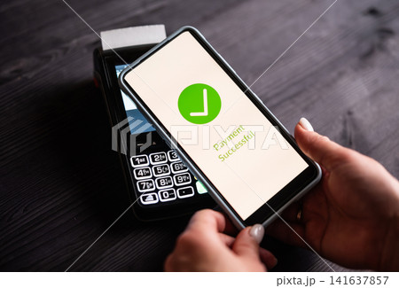 Girl Paying With Smartphone Over Wireless Terminal With Payment Approved Status On A Screen Girl Paying With Smartphone Over Wireless Terminal With Payment Approved Status On A Screen 141637857