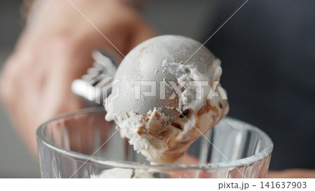 Hands Scooping A Round Portion Of Delicious Ice Cream With Topping Using An Ice Cream Scoop Hands Scooping A Round Portion Of Delicious Ice Cream With Topping Using An Ice Cream Scoop 141637903