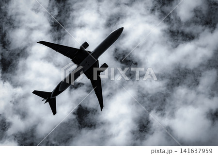 Commercial passenger airplane flying overhead beneath dramatic textured clouds. Modern aviation, airline transportation, aerospace engineering, air travel and dynamic weather. Flight technology. Commercial passenger airplane flying overhead beneath dramatic textured clouds. Modern aviation, airline transportation, aerospace engineering, air travel and dynamic weather. Flight technology. 141637959