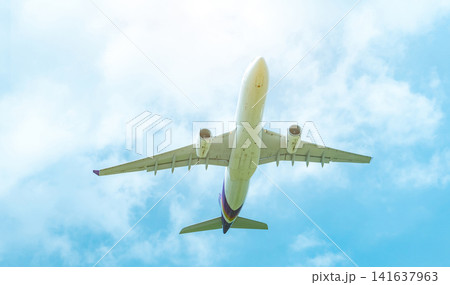 Commercial airline flying on blue sky and white fluffy clouds. Under view of airplane flying. Passenger plane after take off or going to landing flight. Vacation travel abroad. Air transportation. Commercial airline flying on blue sky and white fluffy clouds. Under view of airplane flying. Passenger plane after take off or going to landing flight. Vacation travel abroad. Air transportation. 141637963
