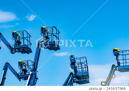 Articulated boom lift fleet with telescopic aerial work platforms against sky. Construction equipment rental, industrial maintenance, hydraulic access systems, engineering services and elevated work. Articulated boom lift fleet with telescopic aerial work platforms against sky. Construction equipment rental, industrial maintenance, hydraulic access systems, engineering services and elevated work. 141637966