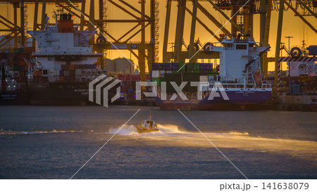 BARCELONA, SPAIN - NOVEMBER 09, 2018 - Container cargo ships and docks with cranes loading and unloading goods and the pilot boat in the sea 141638079