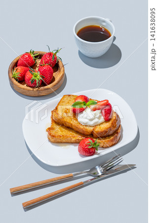 Brioche toasts with strawberries and whipped cream, drizzled with honey on a plate Brioche toasts with strawberries and whipped cream, drizzled with honey on a plate 141638095