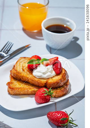 Brioche toasts with strawberries and whipped cream, drizzled with honey on a plate Brioche toasts with strawberries and whipped cream, drizzled with honey on a plate 141638096