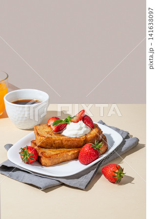 Brioche toasts with strawberries and whipped cream, drizzled with honey on a plate Brioche toasts with strawberries and whipped cream, drizzled with honey on a plate 141638097