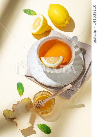 A cup of hot tea with fresh lemon, ginger, mint on a bright yellow background A cup of hot tea with fresh lemon, ginger, mint on a bright yellow background 141638110