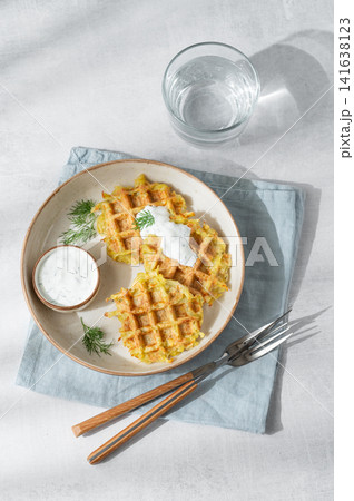 Vegetarian potato waffles with natural yogurt and dill on a plate on a light background Vegetarian potato waffles with natural yogurt and dill on a plate on a light background 141638123