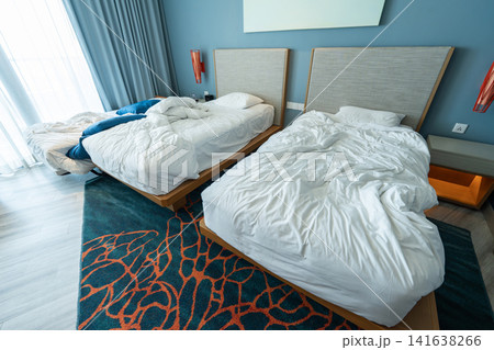 Twin beds and a rollaway extra bed with untidy bedding, a recently occupied family hotel room. Twin beds and a rollaway extra bed with untidy bedding, a recently occupied family hotel room. 141638266