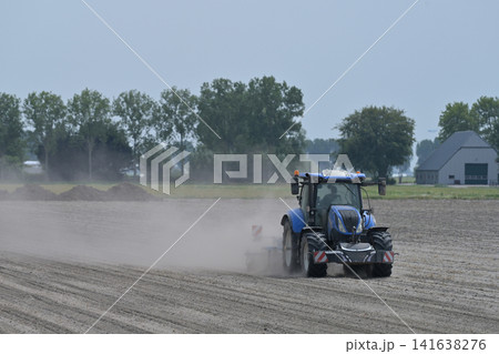 Blue Tractor Cultivating Dry Dusty Field Blue Tractor Cultivating Dry Dusty Field 141638276