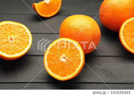 Whole and half of orange fruit on black wooden background. 141638365