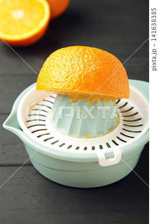 Squeezer and orange fruits on black wooden background. Vertical photo Squeezer and orange fruits on black wooden background. Vertical photo 141638385