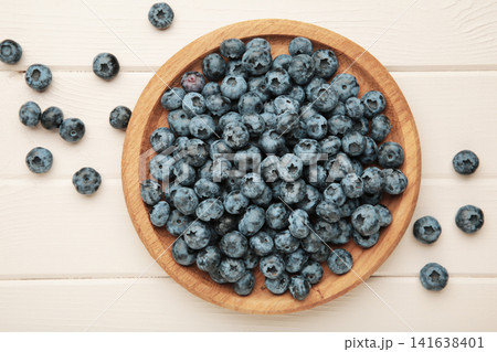 Blueberry on wooden plate on light wooden background. Top view Blueberry on wooden plate on light wooden background. Top view 141638401