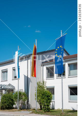 Bavarian, German and European Union flags on flagpoles in front of office building on sunny day in Germany Bavarian, German and European Union flags on flagpoles in front of office building on sunny day in Germany 141638436
