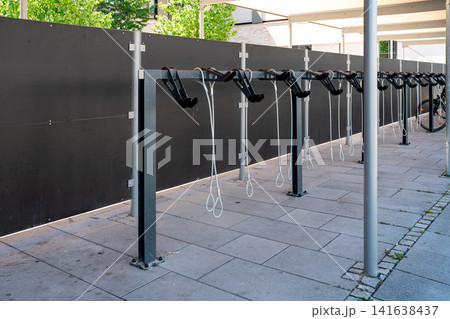 Modern covered bike parking racks in Fuerstenfeldbruck, Bavaria, Germany, empty bicycle parking area in urban street on sunny day Modern covered bike parking racks in Fuerstenfeldbruck, Bavaria, Germany, empty bicycle parking area in urban street on sunny day 141638437