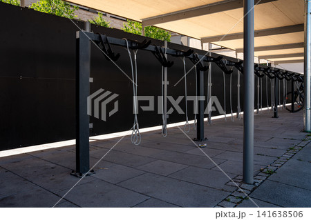 Modern covered bike parking racks in Fuerstenfeldbruck, Bavaria, Germany, empty bicycle parking area in urban street on sunny day Modern covered bike parking racks in Fuerstenfeldbruck, Bavaria, Germany, empty bicycle parking area in urban street on sunny day 141638506