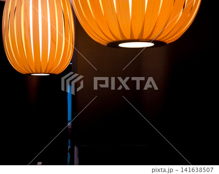Close up of modern wooden pendant lights with warm ambient glow in stylish Munich conference hotel interior, contemporary lighting design detail against dark background in hospitality space 141638507